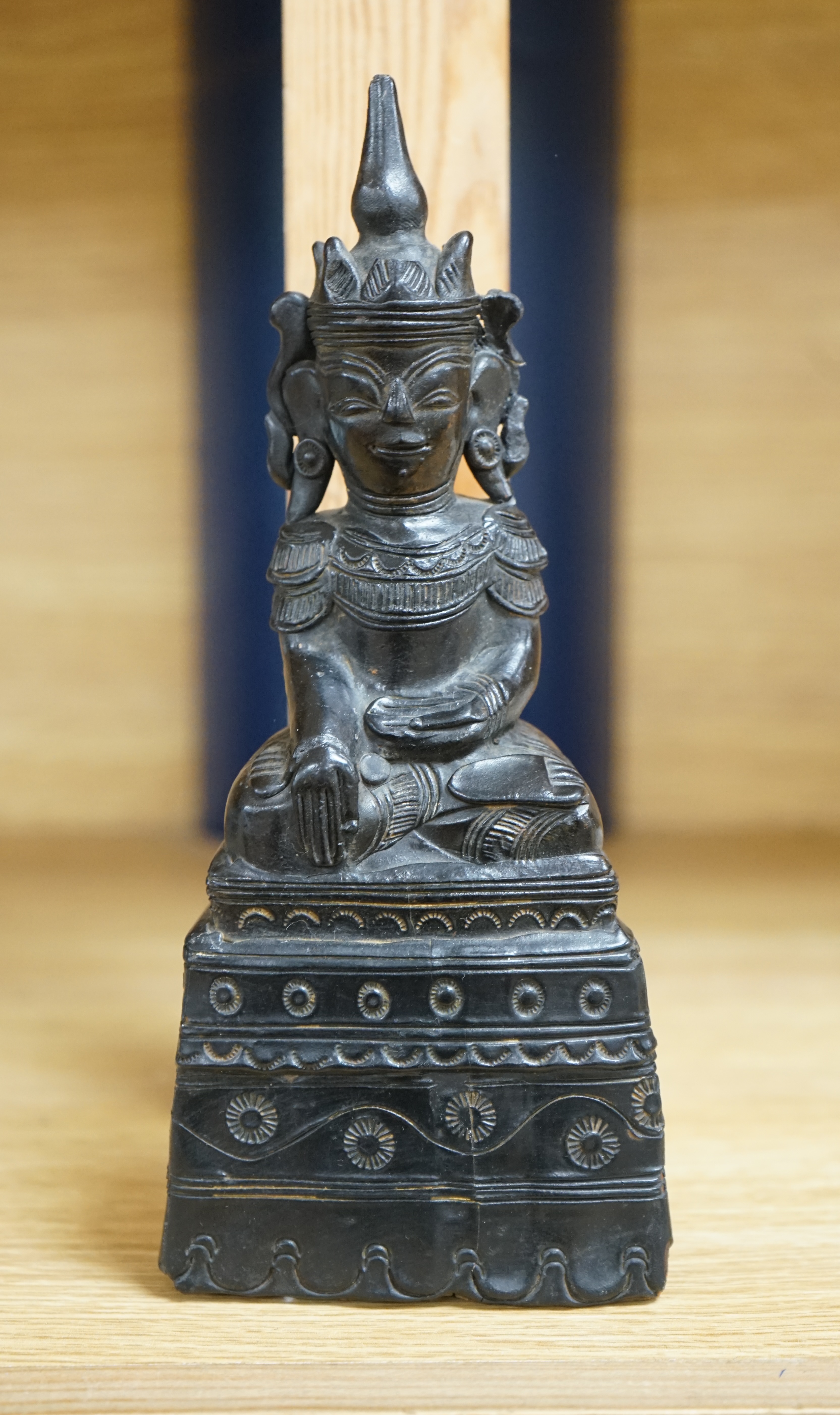 A 19th century Burmese black lacquer and wood seated figure of Buddha, 21cm high. Condition - fair, losses to the lacquer on the reverse